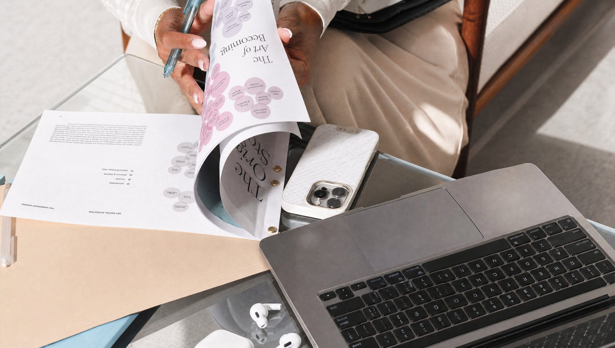 Hands turning the pages of a strategy document with a bubble diagram, beside a laptop.